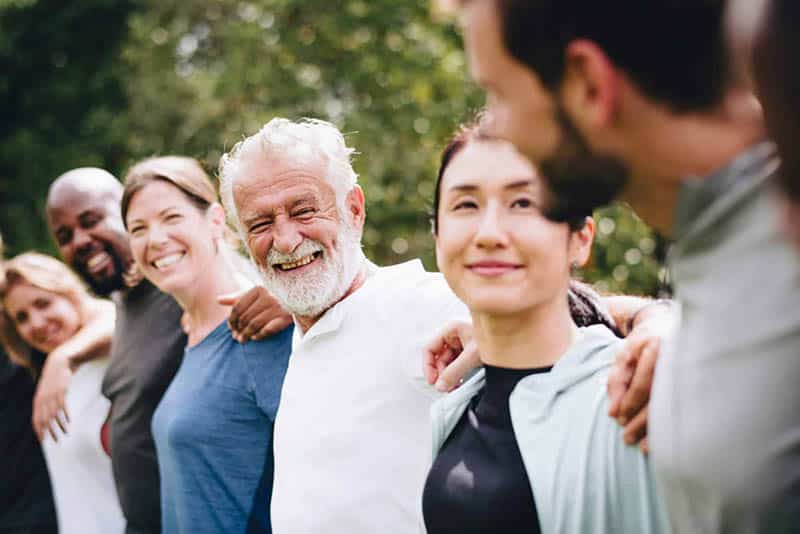 Group of smiling friends of different ages standing together outdoors