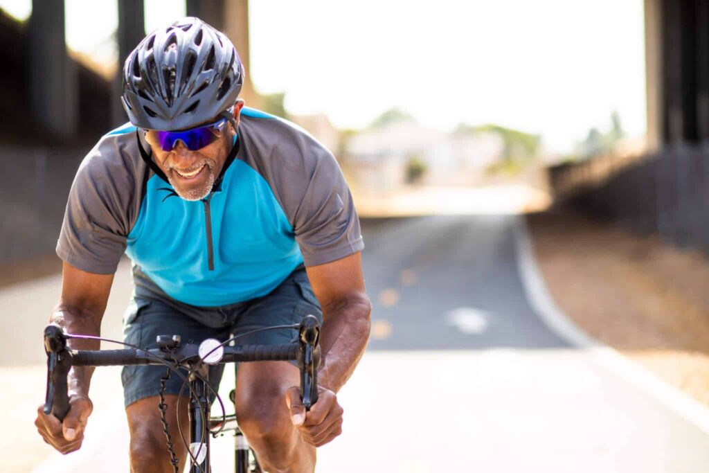Smiling man in helmet cycling on a paved trail