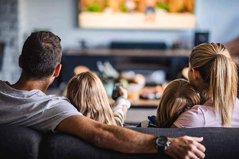 Family of four watching TV together on a couch