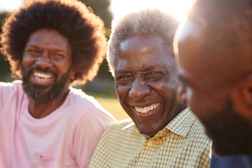 Three smiling Black men of different ages outdoors