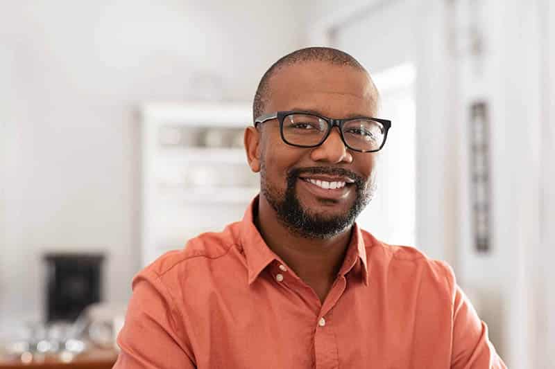 Smiling man with glasses and beard in an orange shirt