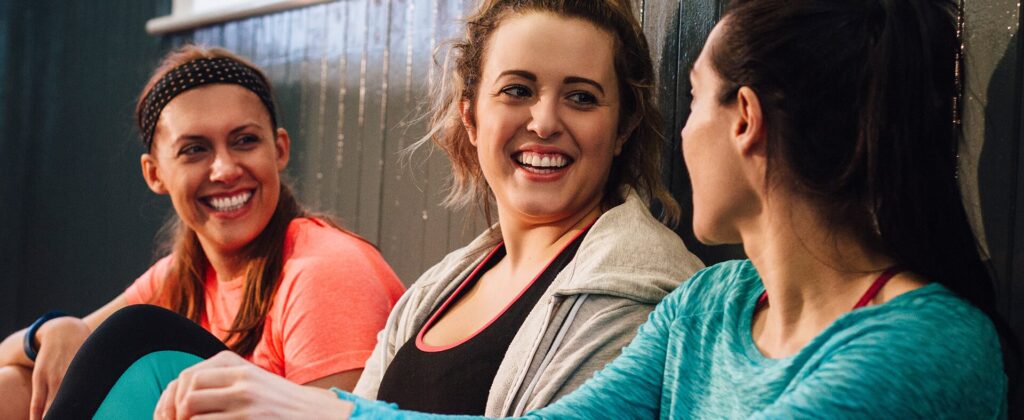 Three smiling women chatting after a workout