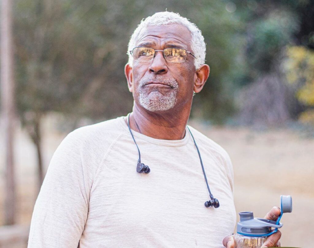 Older man with gray hair holding a water bottle outdoors
