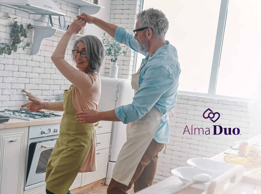 Older couple dancing in a kitchen with Alma Duo logo