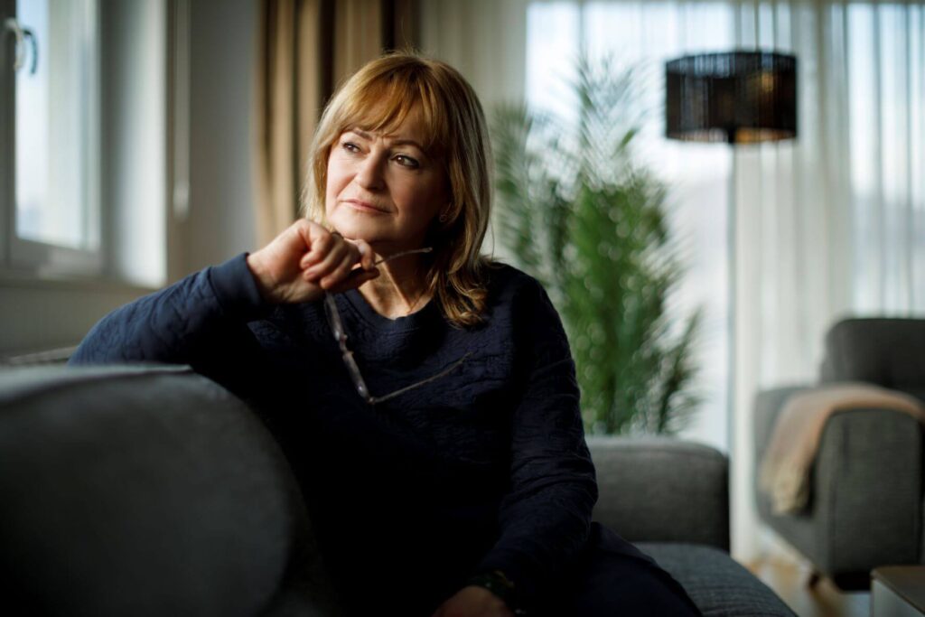 Thoughtful woman sitting on a couch looking away