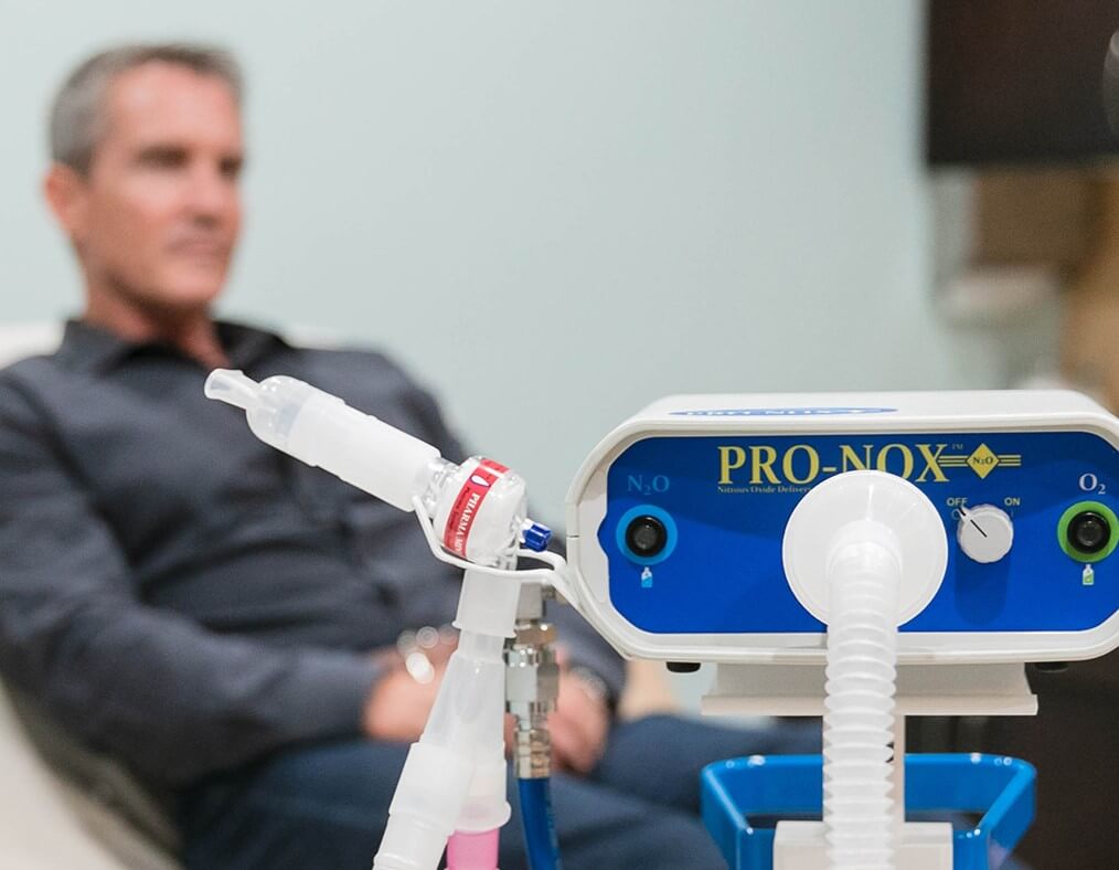 Man seated beside a nitrous oxide sedation machine