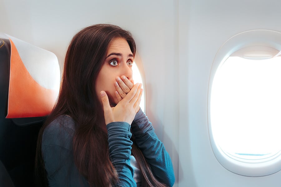 Worried woman covering her mouth in an airplane seat