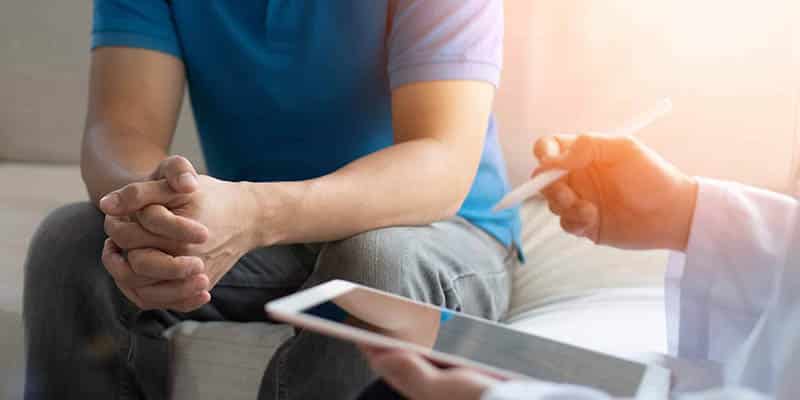 Man in consultation with a doctor holding a tablet