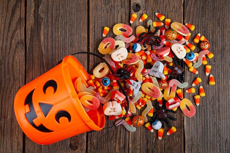 Orange jack-o'-lantern bucket spilling Halloween candy