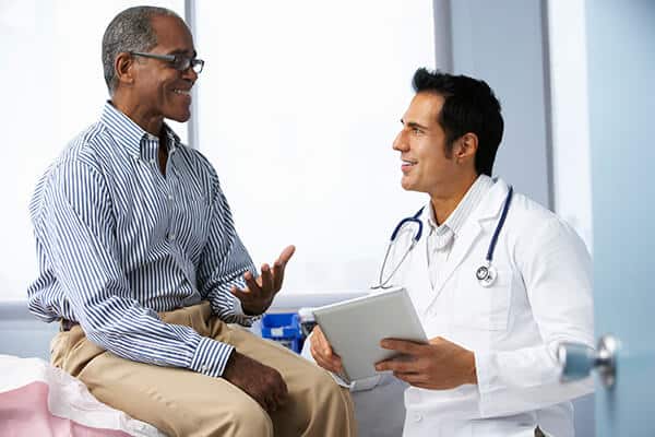 Male doctor with tablet talking with an older male patient