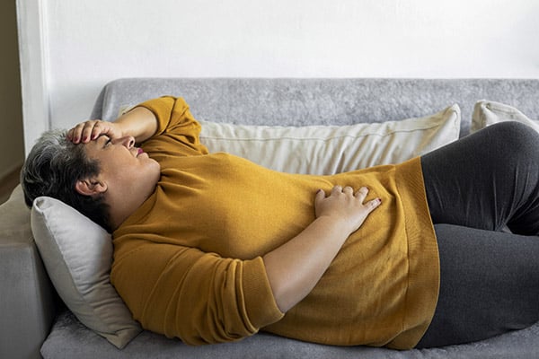 Woman lying on a couch holding her stomach in pain