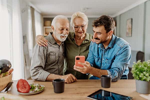 Three men looking at a smartphone together at a kitchen table