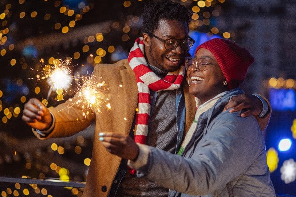 Smiling couple in winter clothing holding sparklers