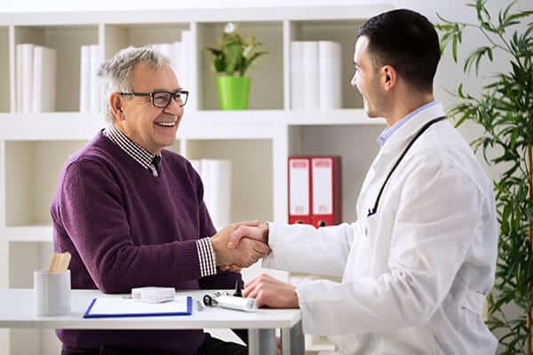 Doctor shaking hands with a smiling older male patient