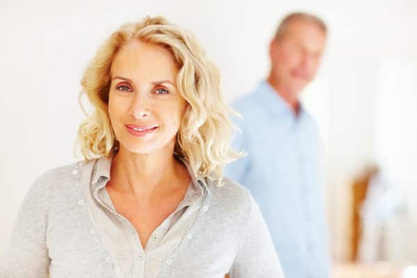 Smiling mature woman with a man blurred behind her