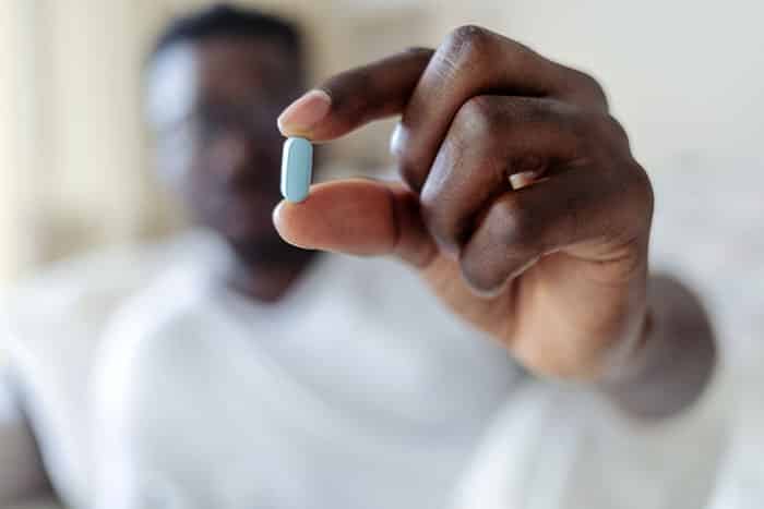 Man holding up a blue pill