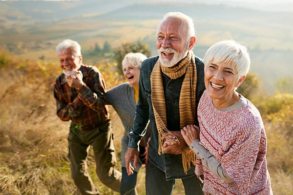 Happy senior friends walking together on a hillside in autumn