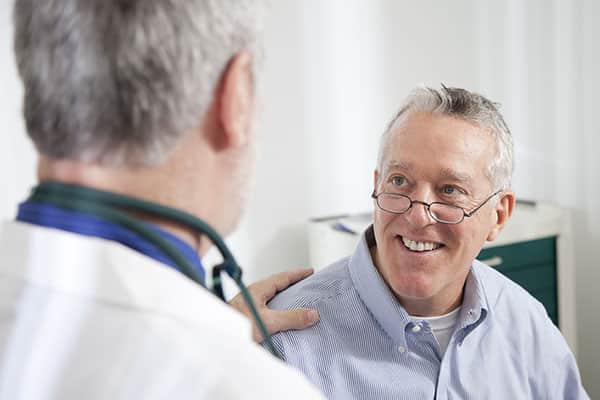 Smiling older male patient talking with a doctor