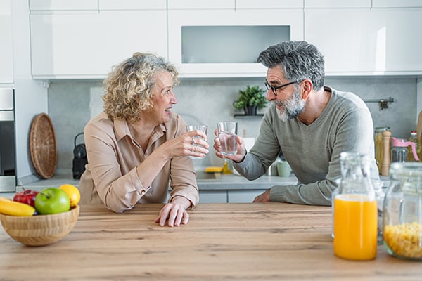Mature couple drinking water together in a kitchen