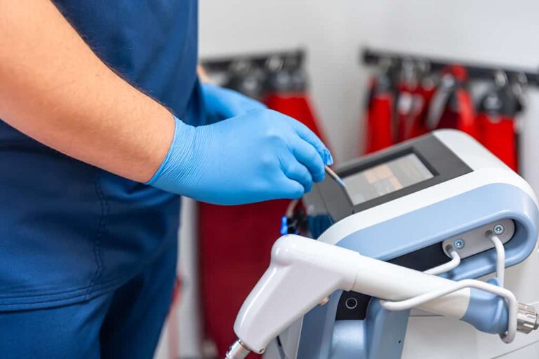Gloved clinician operating a shock wave therapy device