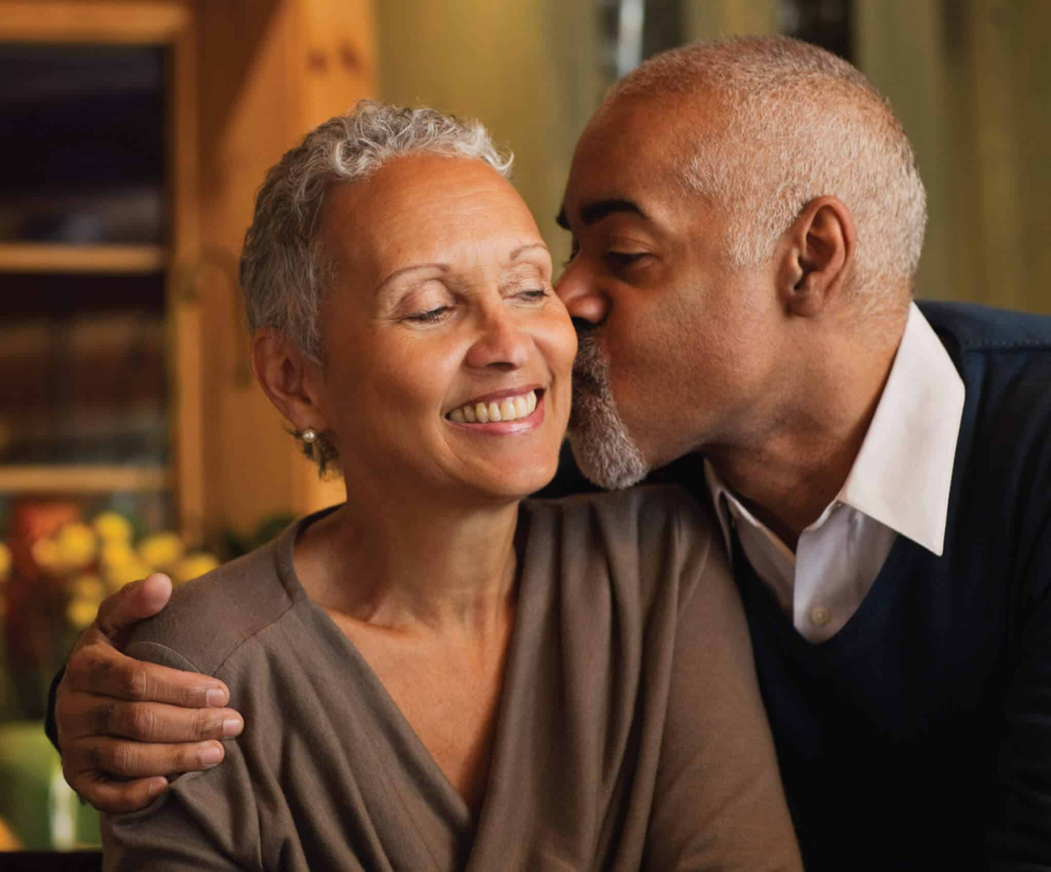 Older man kissing a smiling woman on the cheek