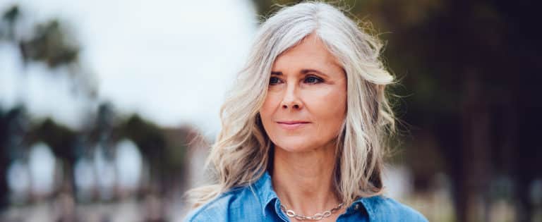Gray-haired woman outdoors with a thoughtful expression