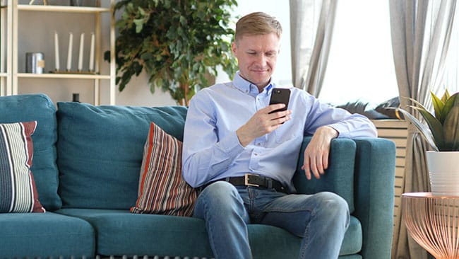 Man sitting on a sofa searching on his smartphone