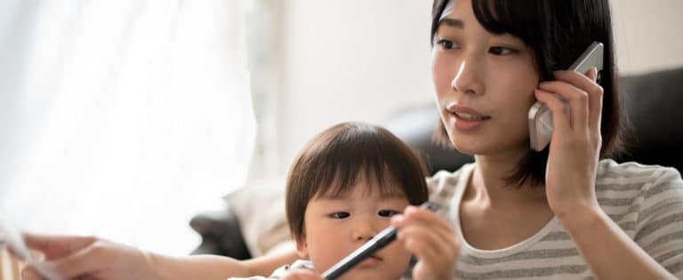 Woman on the phone while a young child draws beside her