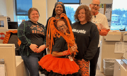 TUG staff members posing together in an office, some in Bengals-themed outfits