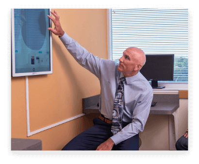 Older physician pointing to an anatomy display on an exam room wall